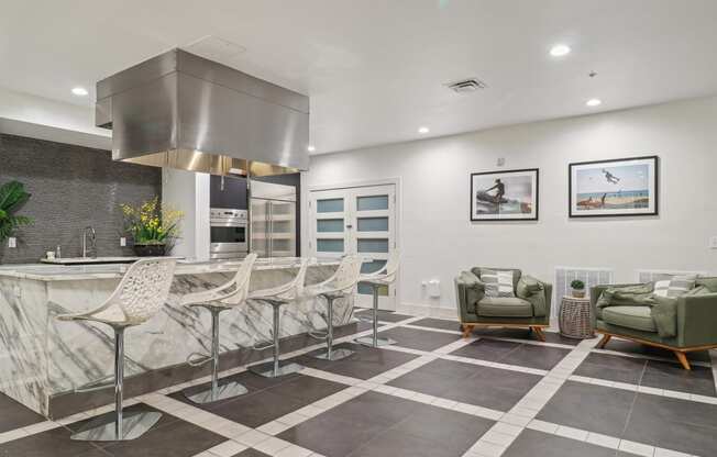 the kitchen has a large island with bar stools and a stainless steel stove top