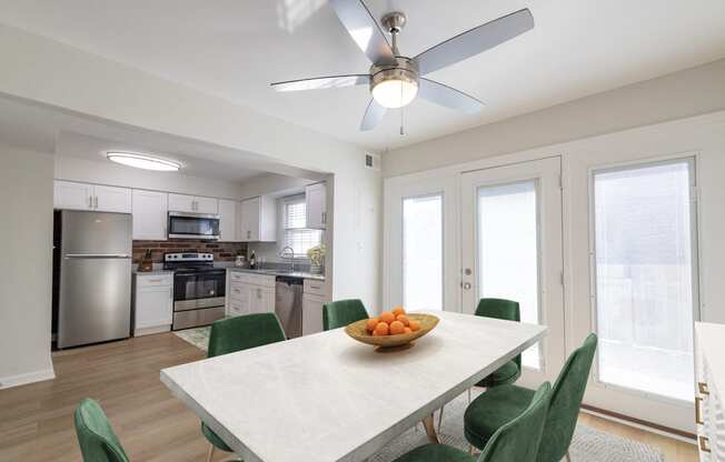 a kitchen and dining room with a white table and green chairs