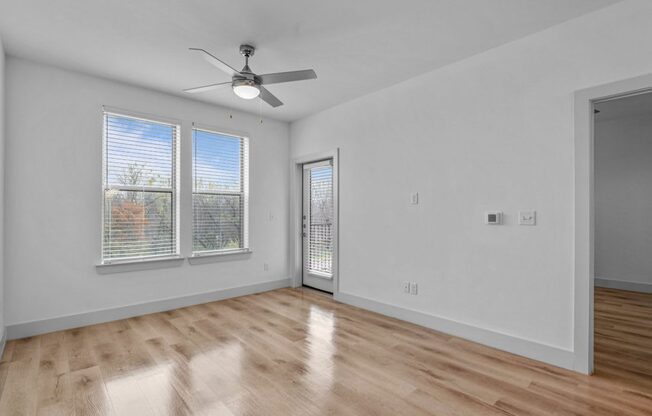 the living room of an empty home with white walls and wood floors