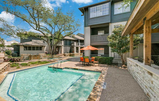 a swimming pool with an umbrella in front of a house