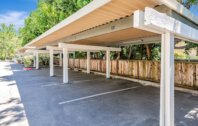 A parking lot with a white canopy and a wooden fence.