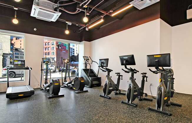 a gym with various exercise equipment on the floor and a window