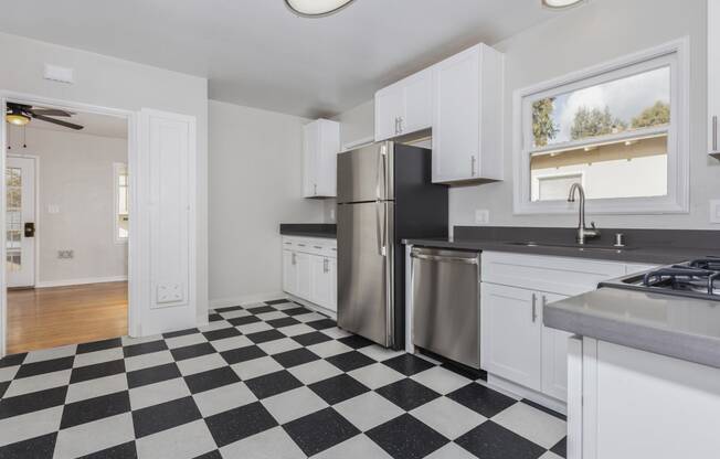 a kitchen with a checkered floor and a stainless steel refrigerator