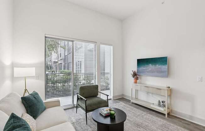 A living room with a white couch, a green chair, a coffee table, and a painting on the wall.