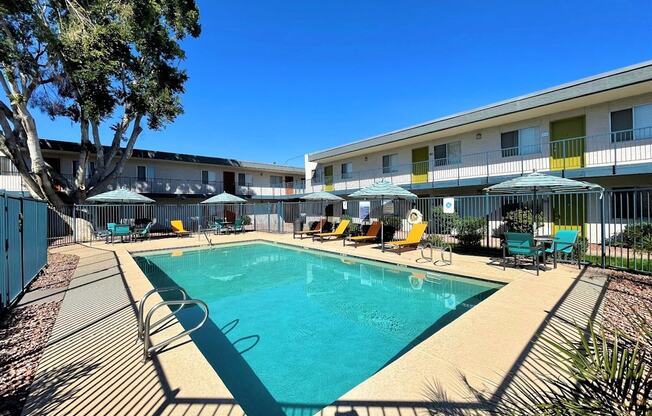 A swimming pool surrounded by chairs and umbrellas in a sunny day.