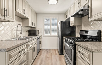 Tiled kitchen with stainless steel microwave, oven, fridge, and fixtures.