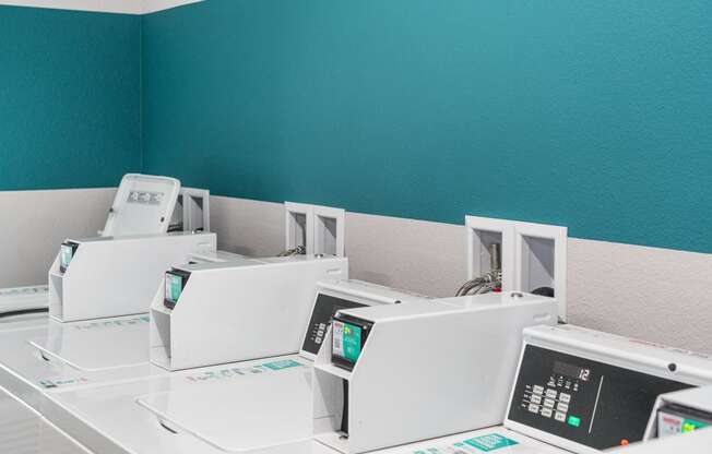 a row of white microwaves in a room with a blue wall