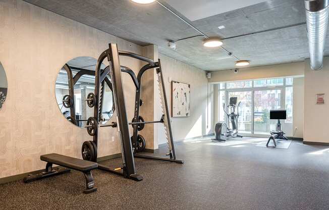 A gym with a mirror, weights, and exercise equipment.