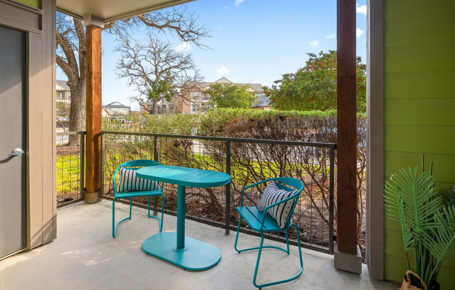 patio with beautiful view of oak trees and. teal table and chairs for relaxing.