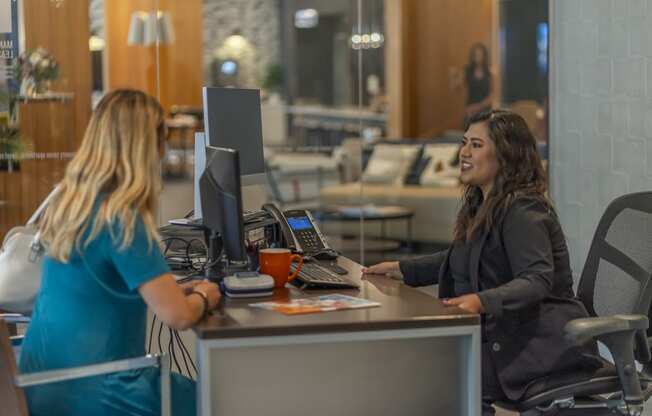 a woman sitting at a desk with a computer in front of her