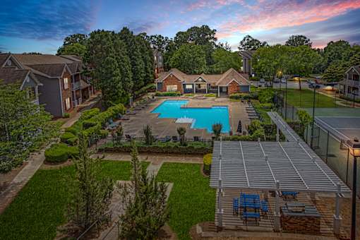 A pool surrounded by a fence and a patio area with chairs.