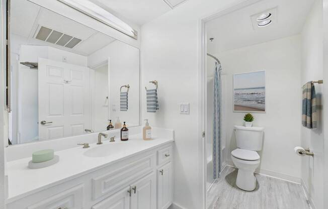 A white bathroom with a toilet, sink, and mirror.