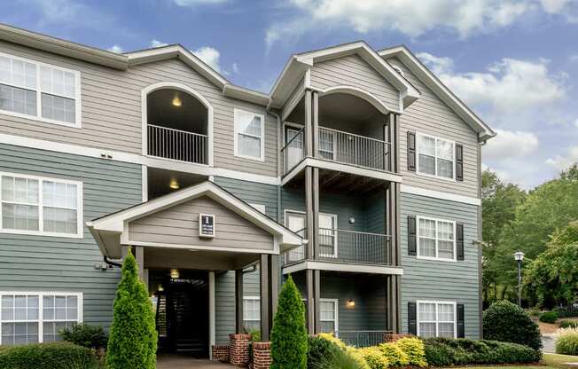 A grey two-story apartment building with a balcony on the second floor.
