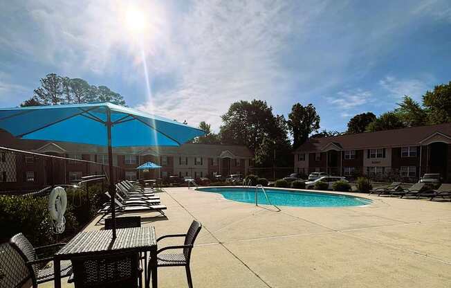 A sunny day at the poolside with tables and chairs.