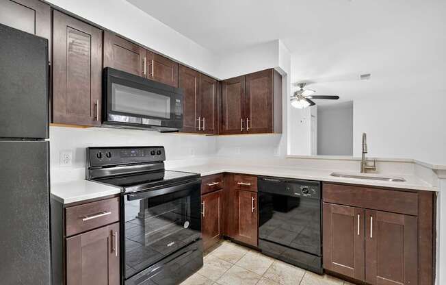 A kitchen with brown cabinets and black appliances.