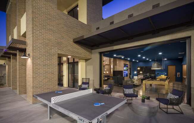 a patio with a ping pong table and chairs