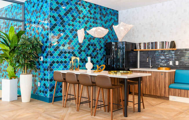 A kitchen with a blue tiled wall and wooden chairs.