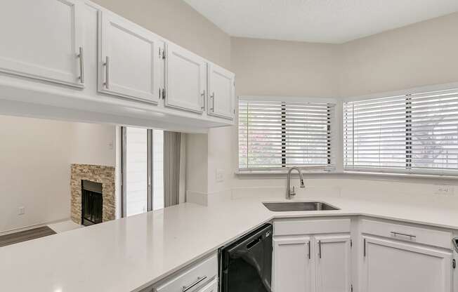 a kitchen with white cabinets and a sink and a window