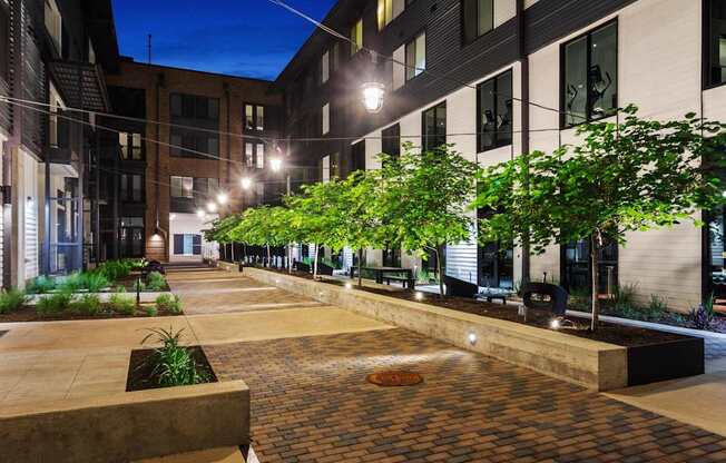 A city courtyard with a brick floor and a row of trees.