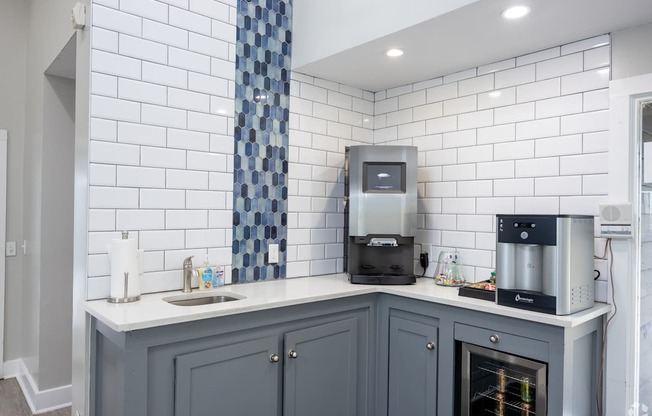 A kitchen with a white tiled wall and a grey cabinet.