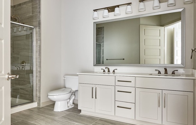 A white bathroom with a toilet, sink, and mirror.