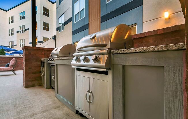 a row of barbecue grills on a patio next to a building at Aster Apartments, Beachwood Ohio