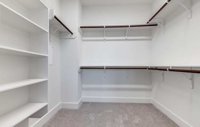 an empty walk in closet with white walls and shelves