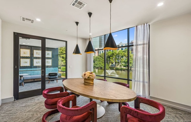 A room with a round table and red chairs.