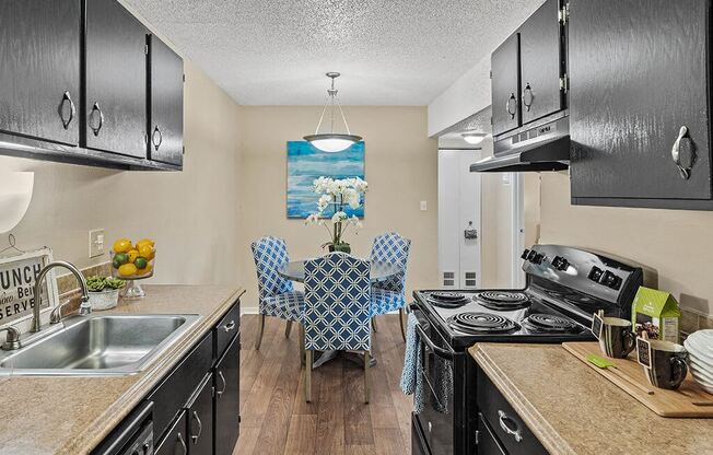 a kitchen with black appliances and a table with chairs