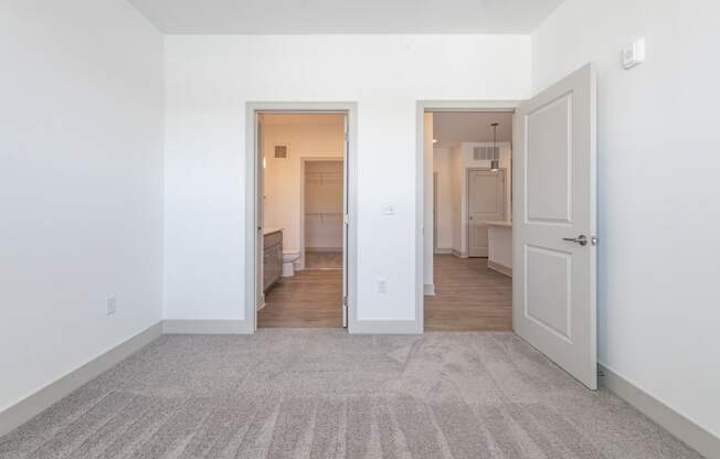 a living room with white walls and a door to a kitchen