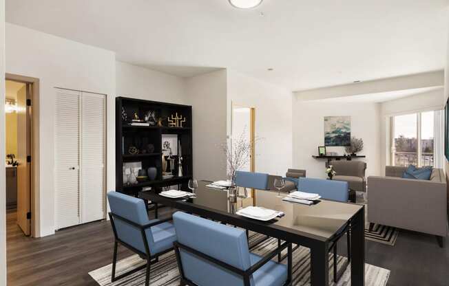 a dining room with a table, 4 blue chairs and the living room behind.at Shoreline Village, Richland, 99352