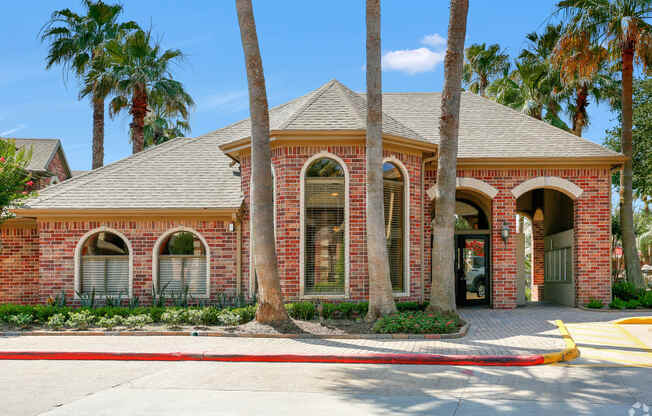 a red brick house with palm trees in front of it