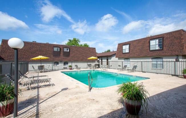A pool area with a blue pool and yellow umbrellas.