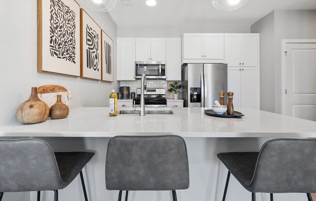 A modern kitchen with white cabinets and a large island with chairs at Madison Prickett Preserve, Pennsylvania, 19067