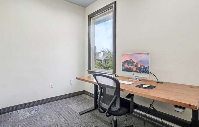 A room with a desk, chair, and a painting on the wall.