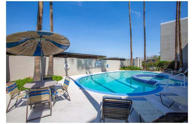 A pool surrounded by chairs and umbrellas with a building in the background.