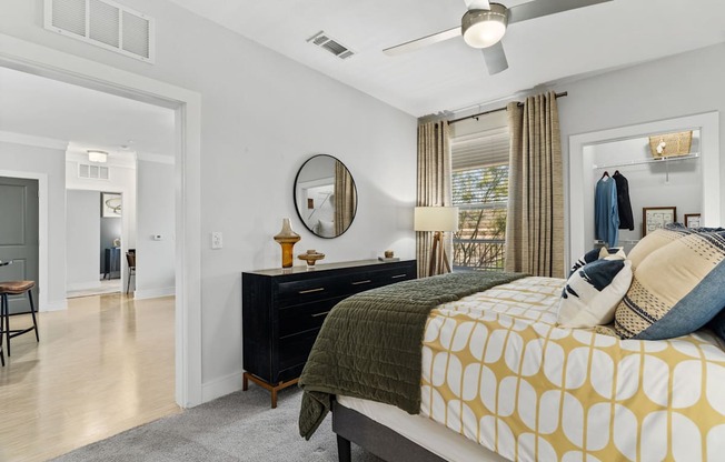A bedroom with a bed, dresser, mirror, and a ceiling fan.