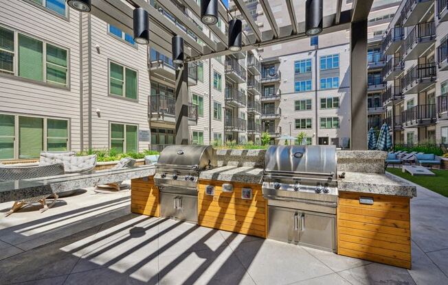 spacious clubhouse with grilling stations and apartments in the background at Link Apartments® 4th Street, Winston-Salem, 27101