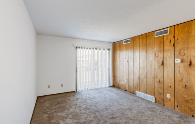 an empty living room with a wooden wall and a sliding glass door