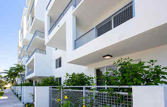 an apartment building with a fence and plants in front of it at Saba Pompano Beach, Pompano Beach, 33062