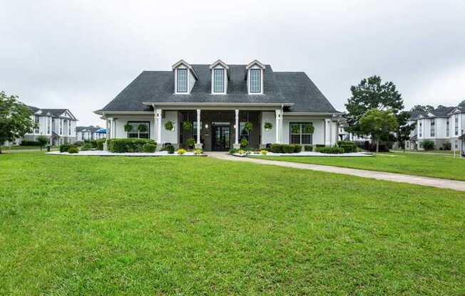 A large white house with a black roof and a green lawn in front.