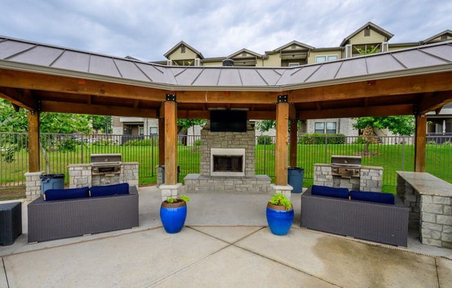 a covered patio with a stone fireplace and a pavilion