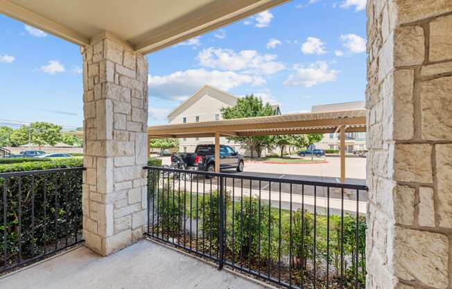 the view of a parking lot from a balcony with a metal gate