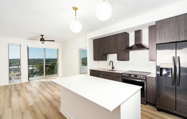 An open kitchen at Modera Nations in Nashville features a spacious island and the choice of light or dark finishes, with skyline views extending the living space.