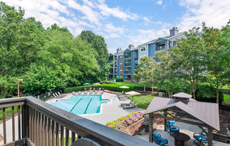 a view of a swimming pool with a patio with chairs and umbrellas