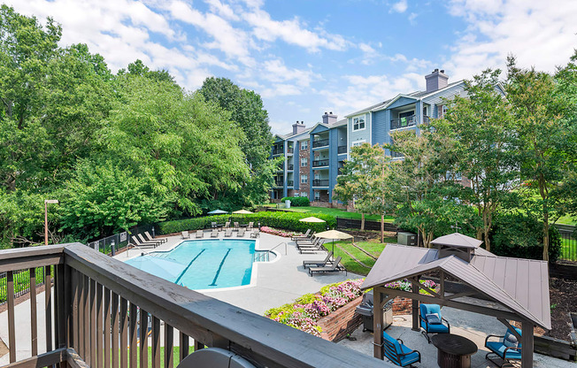 a view of a swimming pool with a patio with chairs and umbrellas