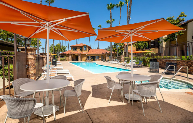 a swimming pool with tables and umbrellas next to it