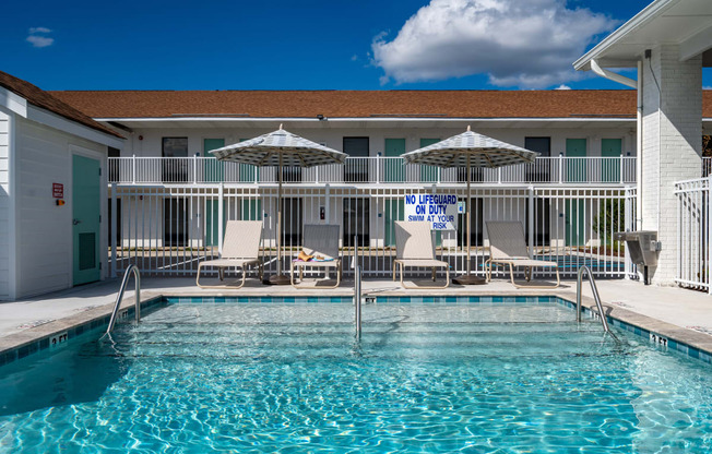 a resort style pool with chairs and umbrellas in front of a building at The Teale Navy Yard, North Charleston, South Carolina