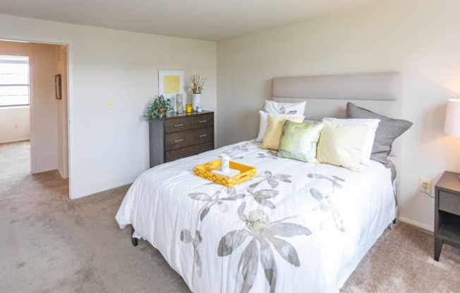 A bedroom with a large bed and a nightstand with a lamp at Dutch Village Apartments, Baltimore