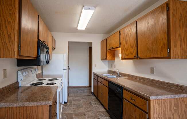 a kitchen with wooden cabinets and a stove and a sink. Fargo, ND Southview Village Apartments